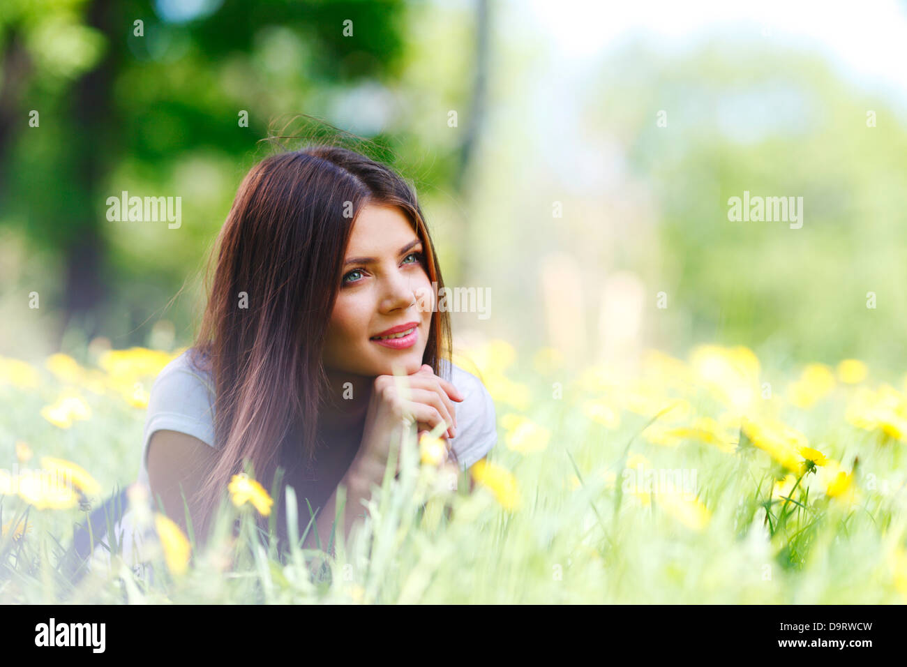 Beautiful young woman lying on grass with flowers Stock Photo - Alamy