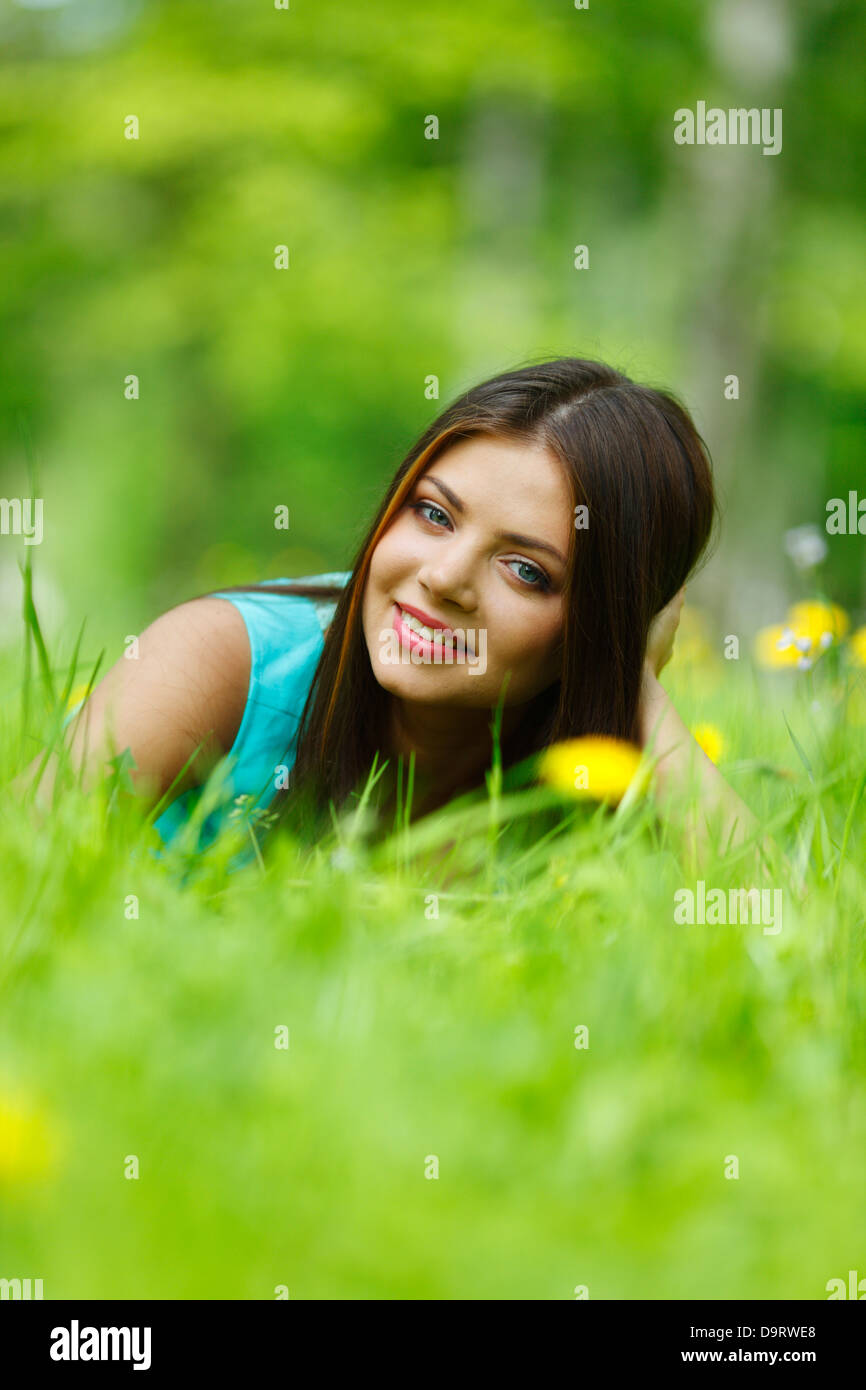 Beautiful young woman lying on grass with flowers Stock Photo - Alamy