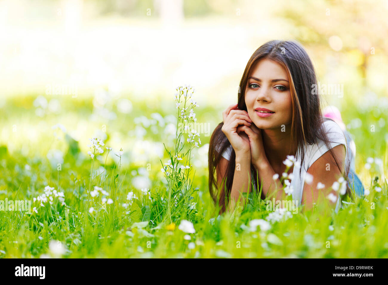 Beautiful young woman lying on grass with flowers Stock Photo - Alamy