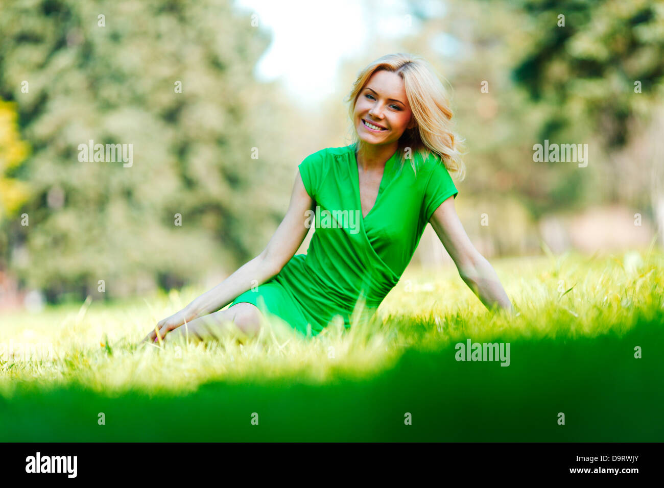 Happy young woman sitting on grass Stock Photo - Alamy
