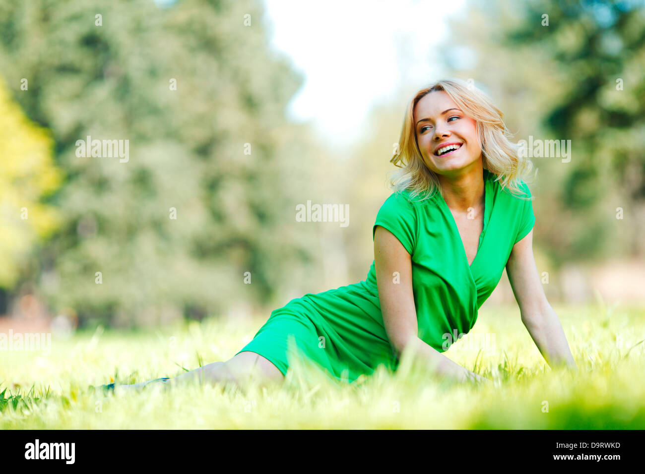 Happy young woman sitting on grass Stock Photo - Alamy