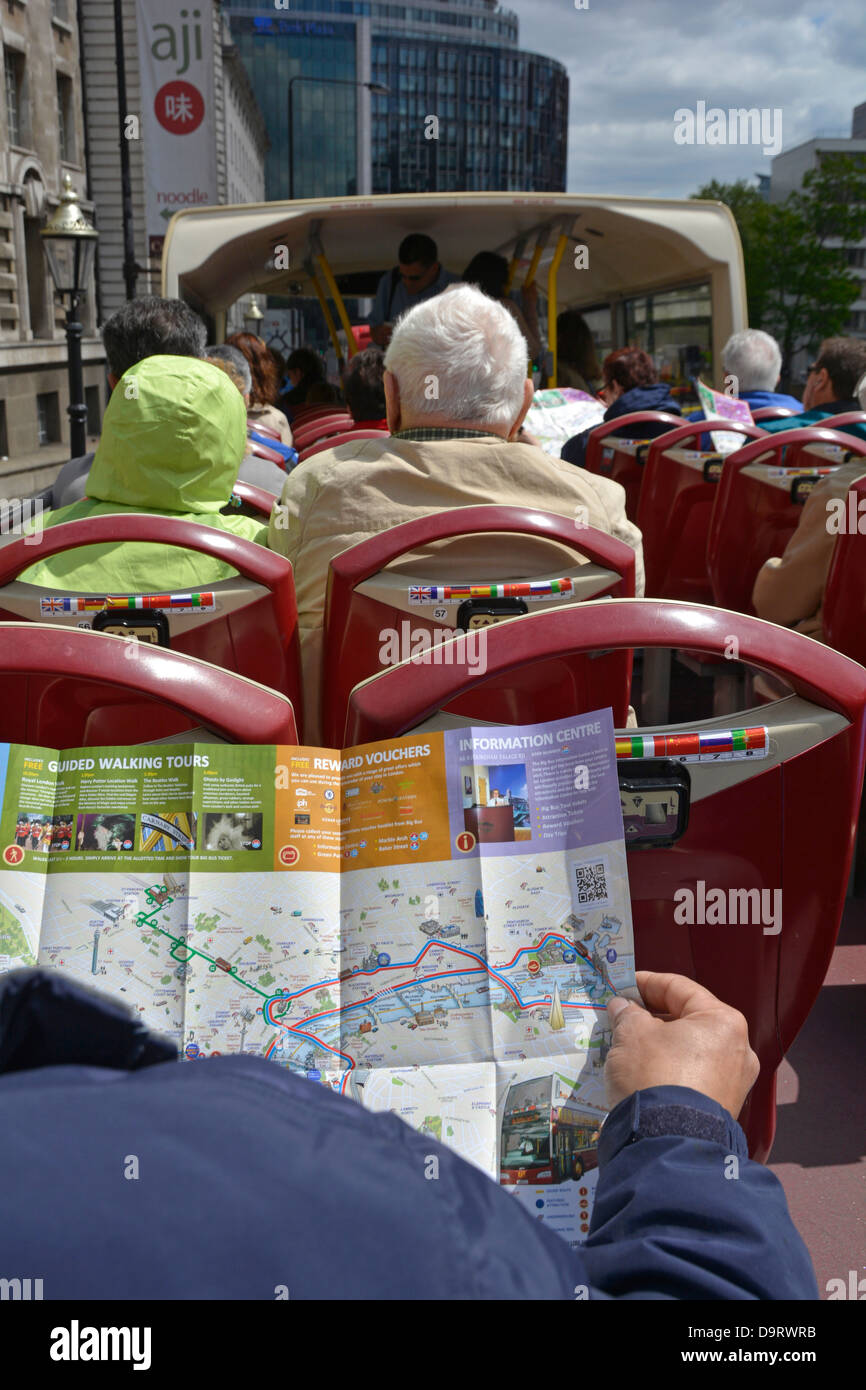 Tourist on open top London tour bus checking the route and locations on free folded map Stock Photo