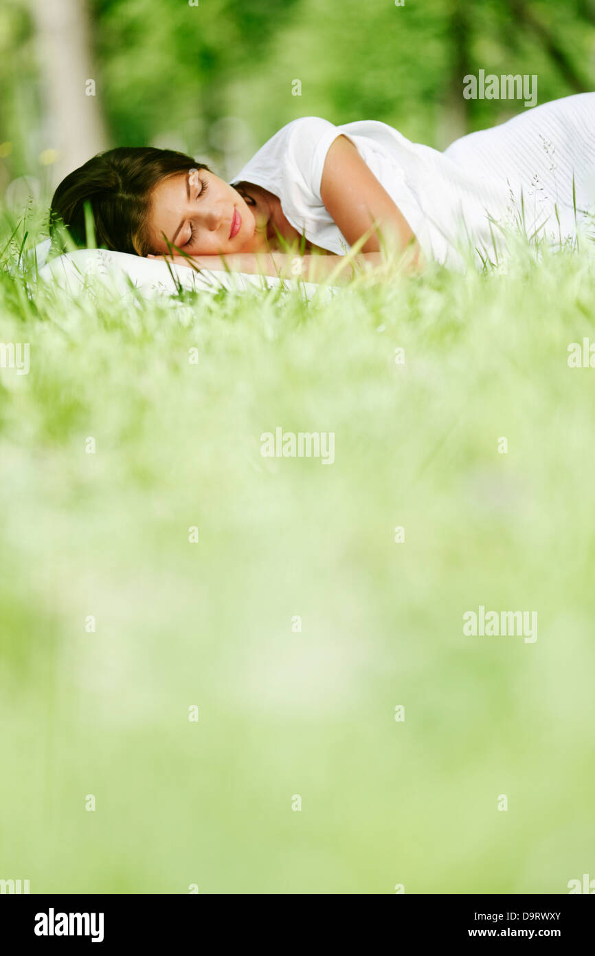 Young woman sleeping on soft pillow in fresh spring grass Stock Photo
