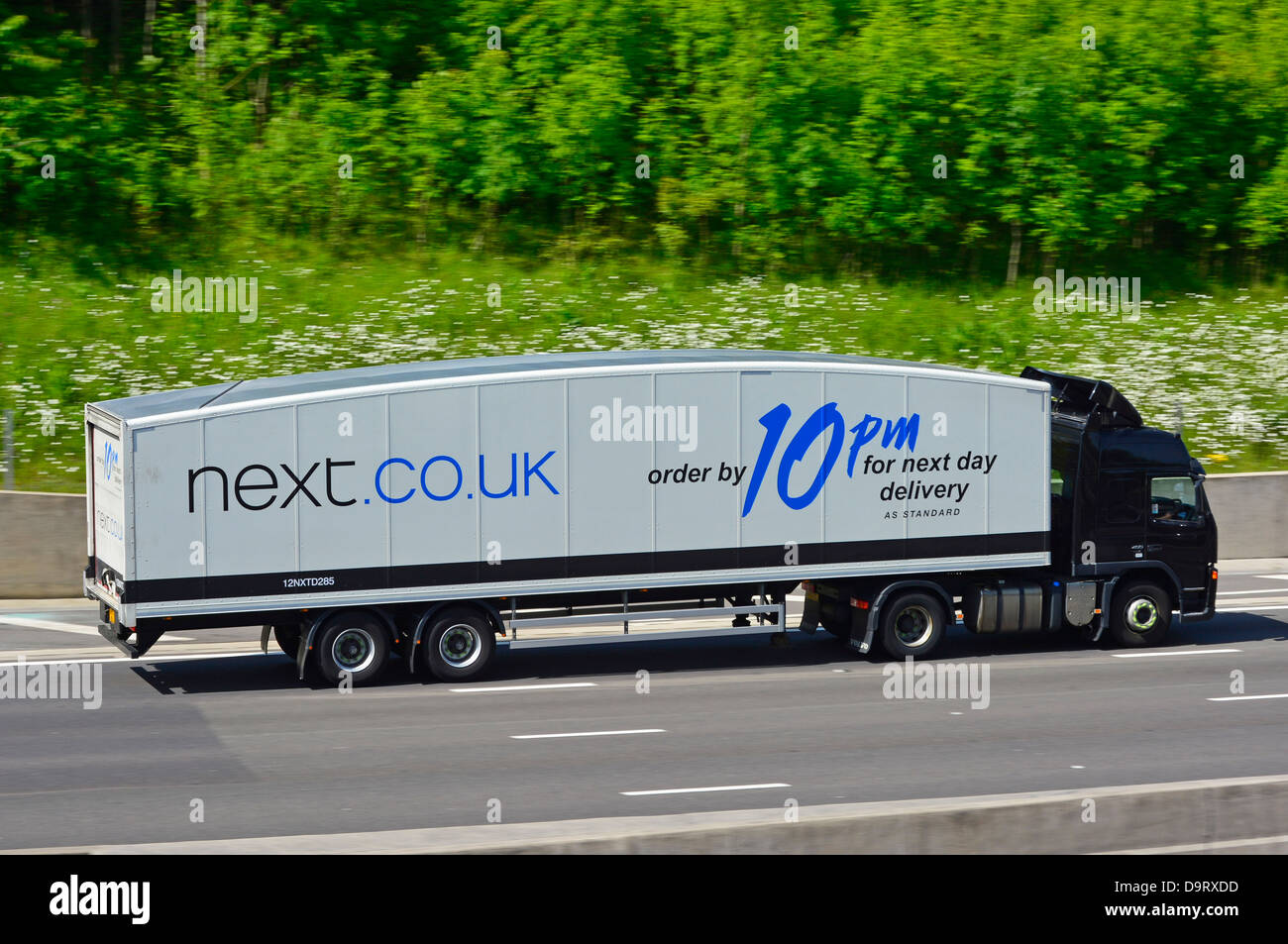 Articulated lorry and trailer with large advert promoting Next store online next day delivery service Stock Photo