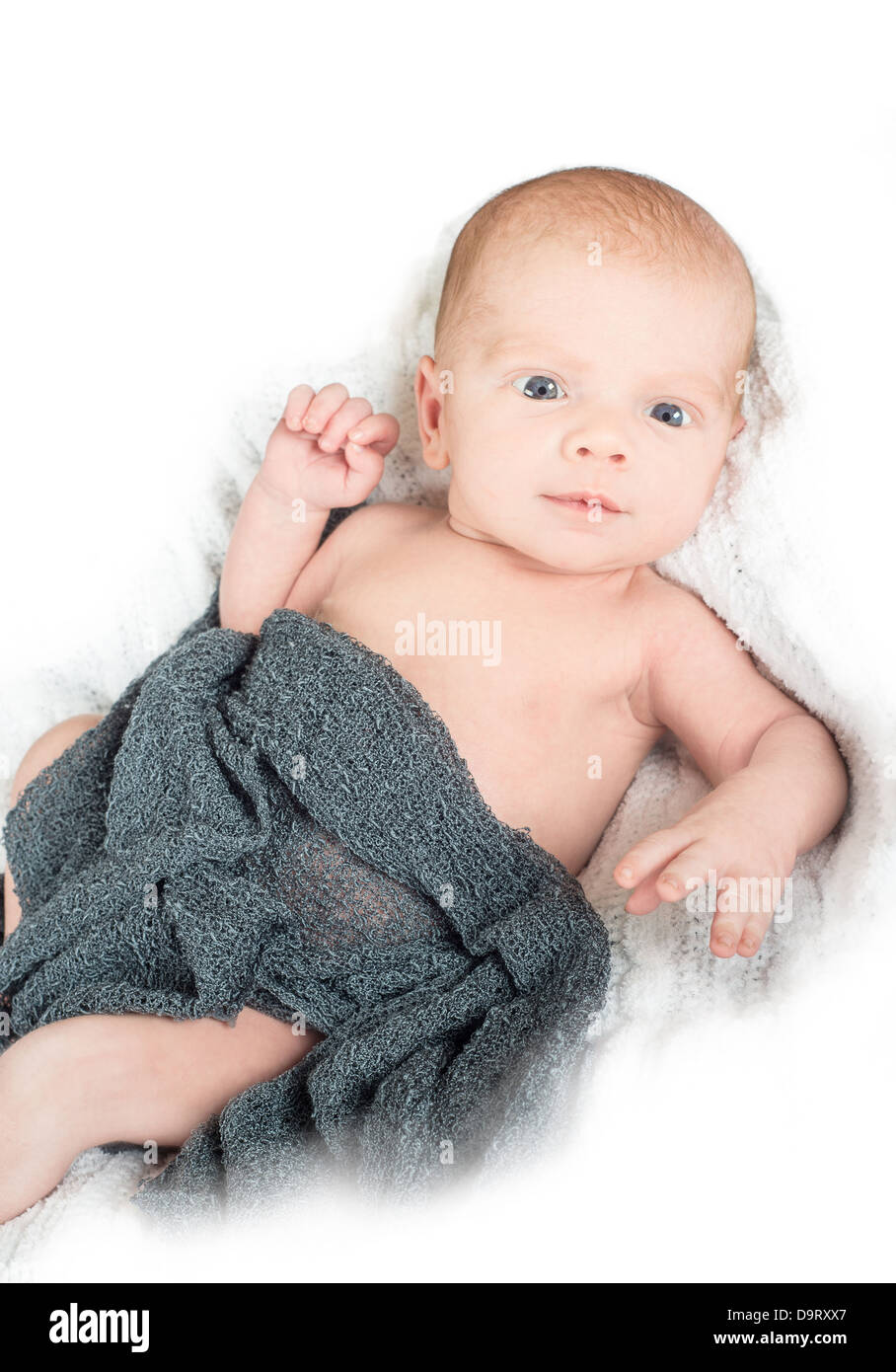 Wide awake newborn with a surprised look on his face on a white knit
