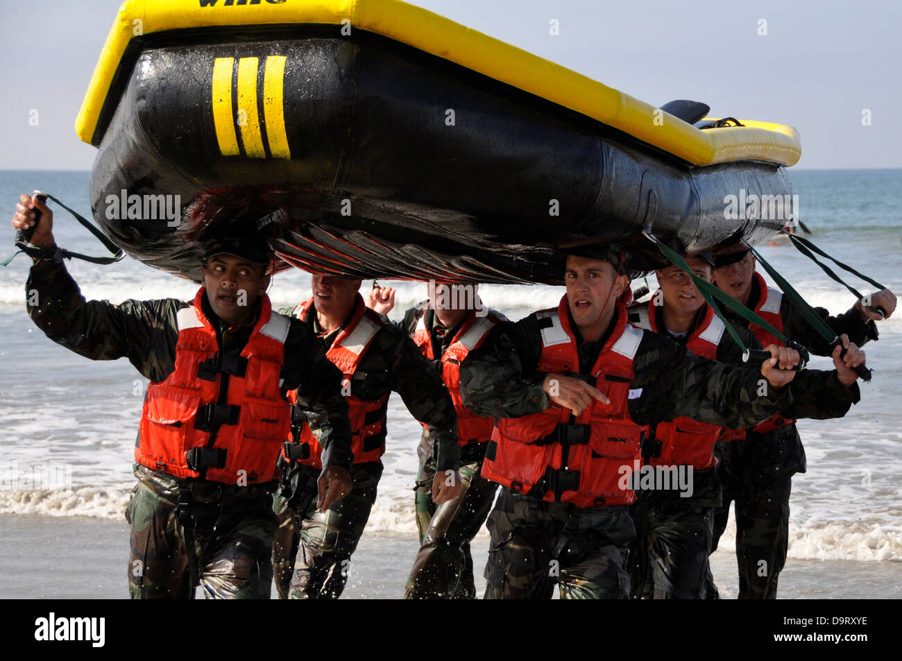 Navy SEAL candidates carry a raft during surf passage exercises on the