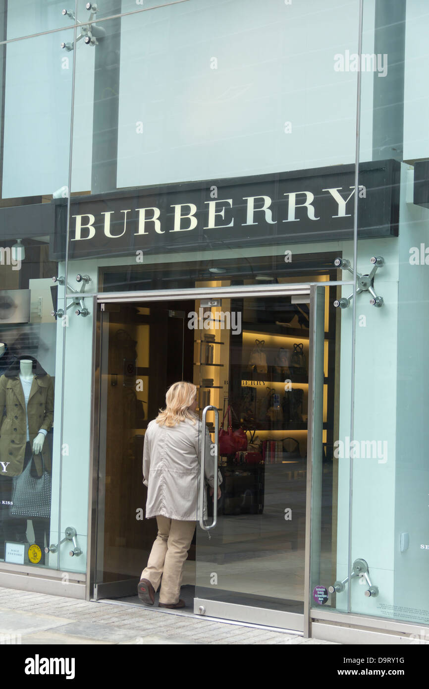 Woman entering the Burberry store on New Cathedral Street in Manchester. Burberry is an iconic British luxury fashion brand. Stock Photo