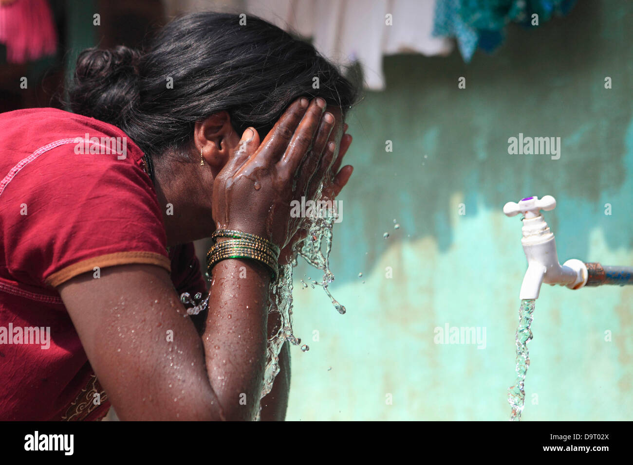 Nov 28, 2012 - Belgaum, Karnataka, India - A woman washes her face in Belgaum where Veolia runs a Pilot project to supply 24 hours tap water to the houses in the slums. Companies are increasingly targeting the Bottom Of Pyramid Markets, the poor, in the developing countries like India to drive future growth and profits. (Credit Image: © Subhash Sharma/ZUMAPRESS.com) Stock Photo