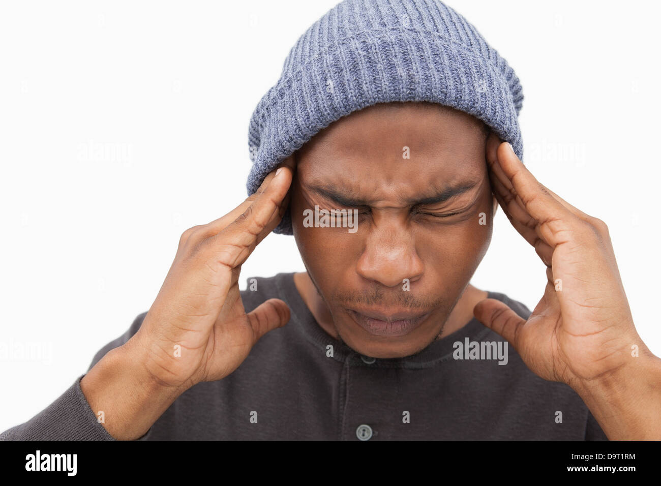Man in beanie hat wincing with pain of headache Stock Photo Alamy