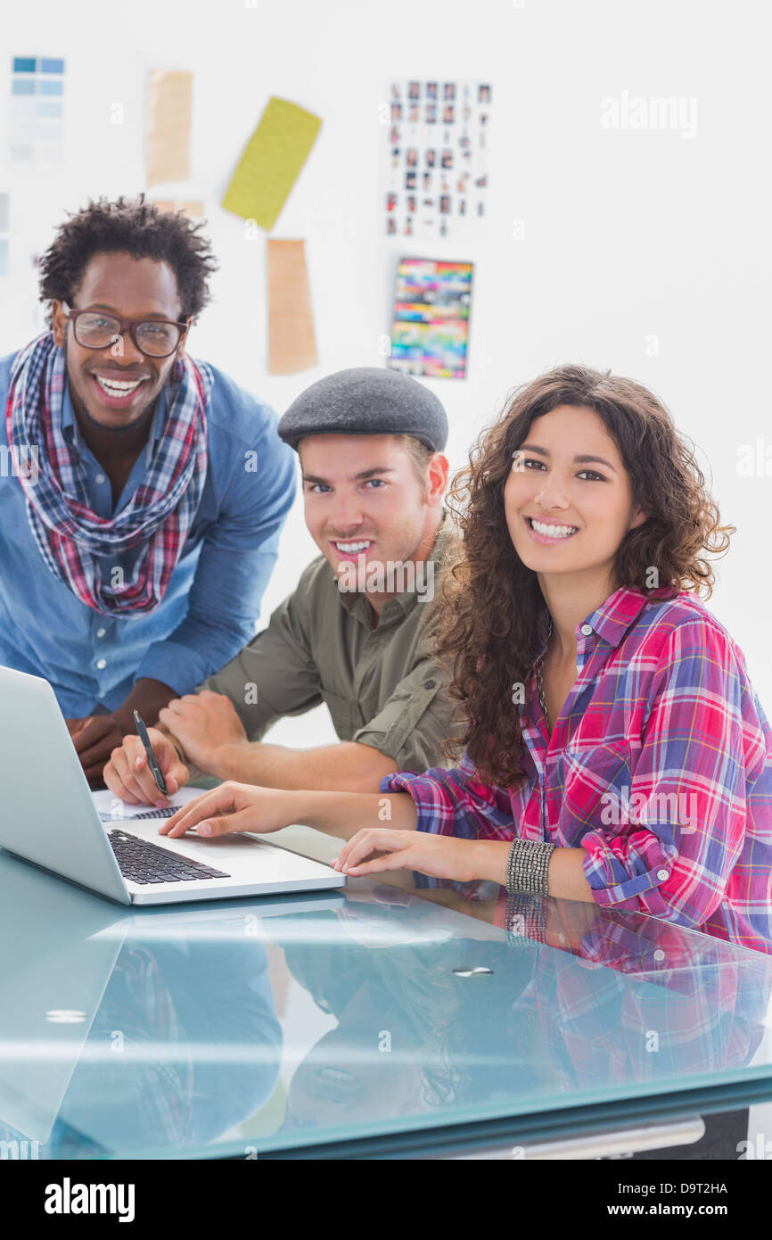Creative team working together on laptop and smiling at camera Stock ...