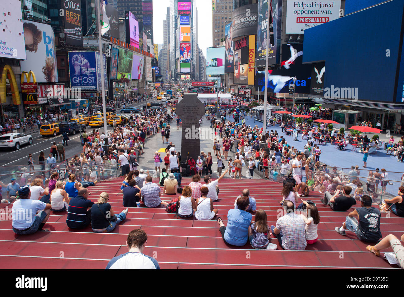 CROWD SITTING ON RED STEPS TKTS CENTER TIMES SQUARE MIDTOWN MANHATTAN