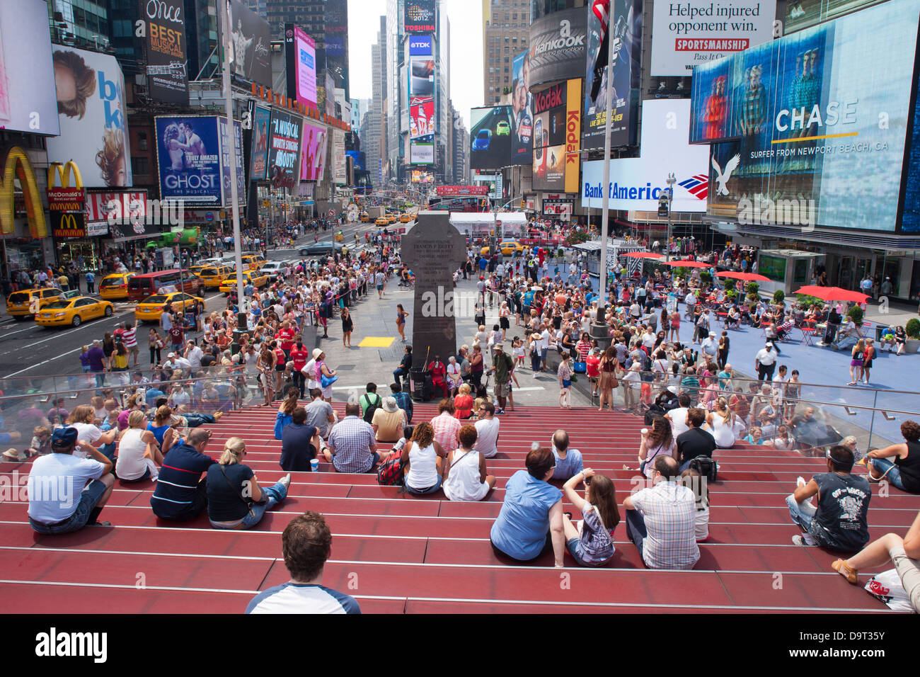 CROWD SITTING ON RED STEPS TKTS CENTER TIMES SQUARE MIDTOWN MANHATTAN NEW YORK CITY USA Stock