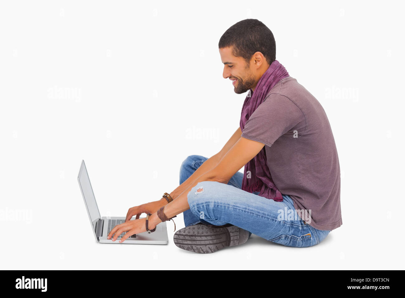 Man wearing scarf sitting on floor using laptop Stock Photo