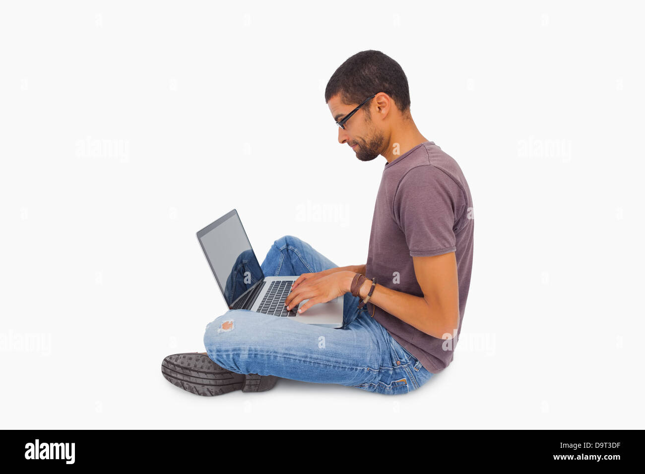 Man wearing glasses sitting on floor using laptop Stock Photo