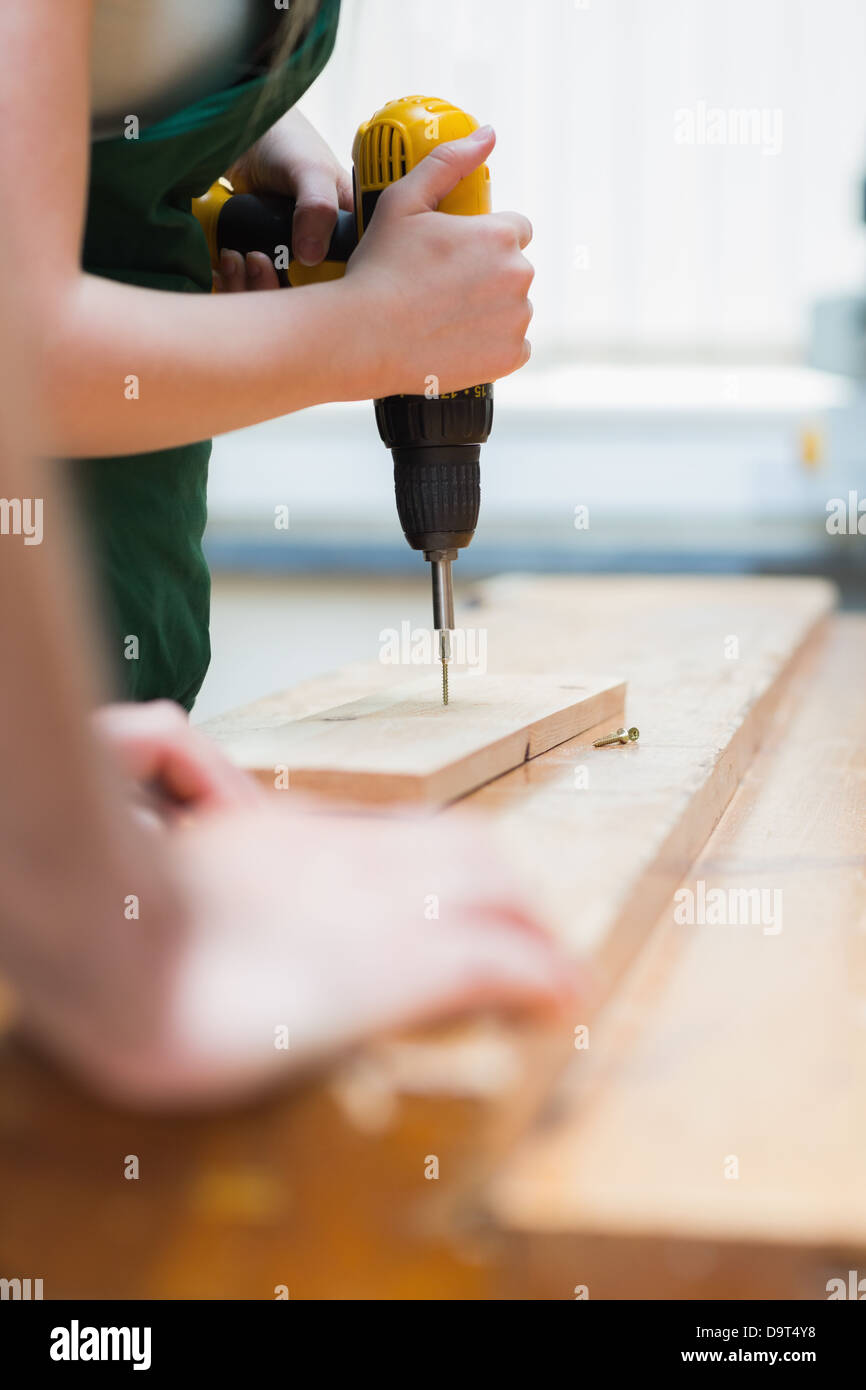 Drilling a hole in a wooden board on the workbench Stock Photo