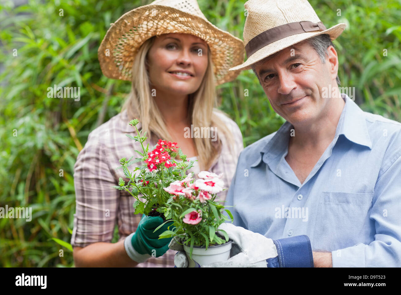 Blonde woman and man holding potted plant Stock Photo - Alamy