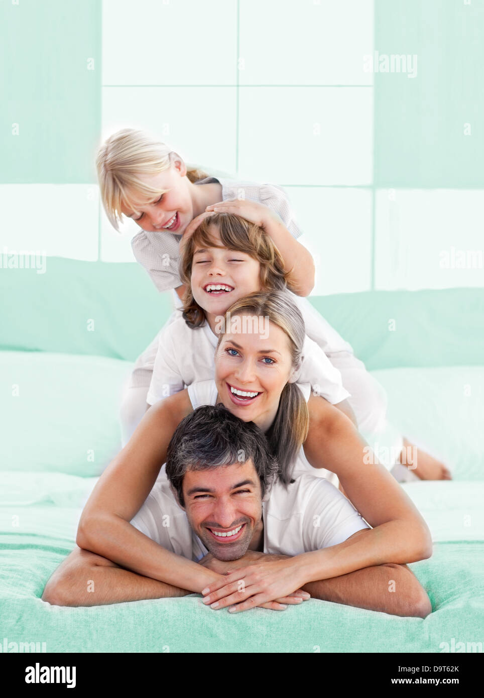 Smiling family piled on top of dad Stock Photo