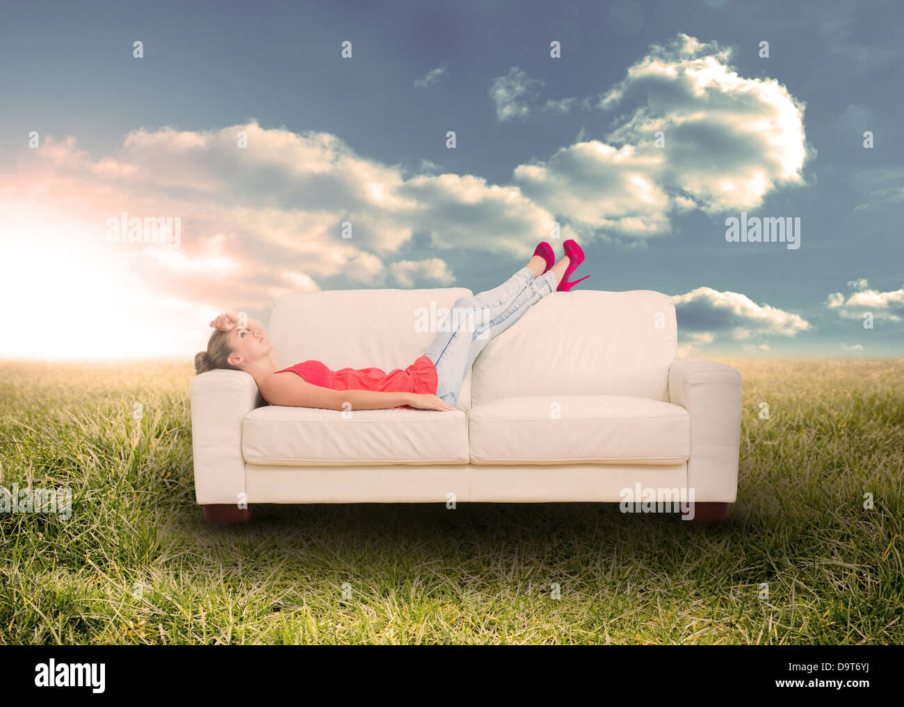 Woman relaxing on couch in field Stock Photo