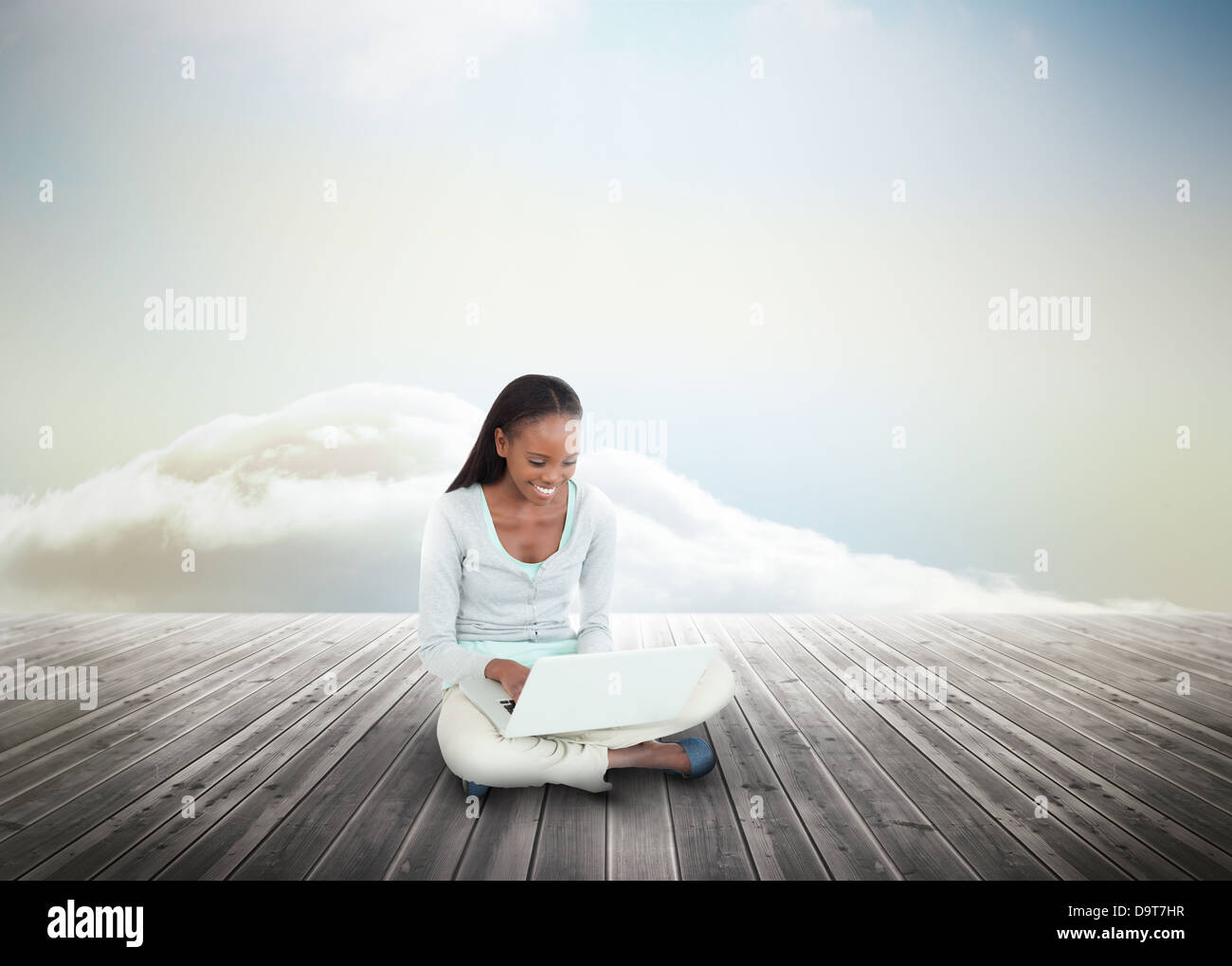 Cute woman using laptop over wooden boards leading out to the horizon Stock Photo