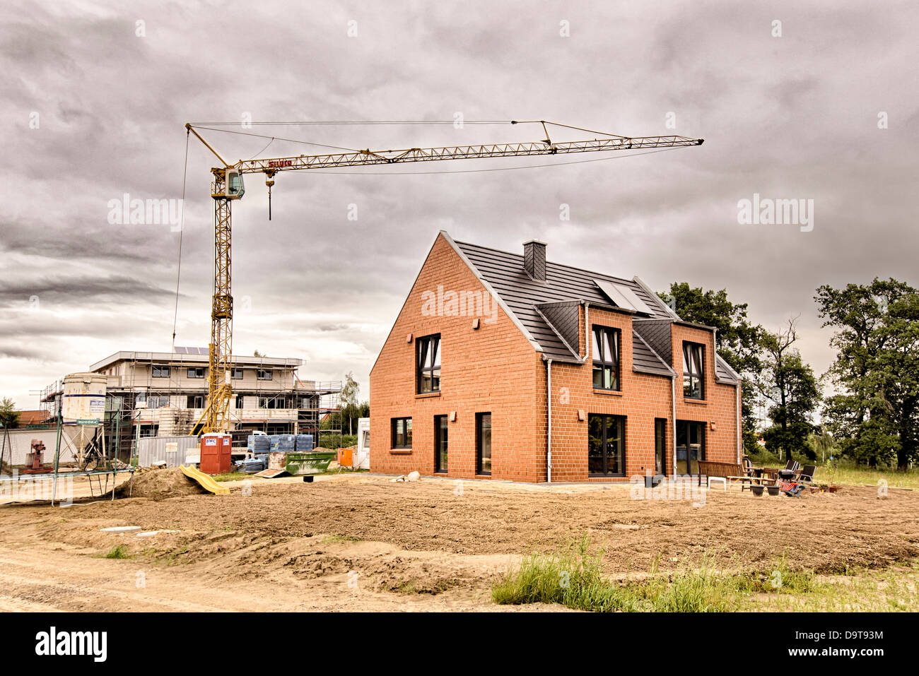 Dark clouds above a developing area with complete residential house and construction site Stock Photo