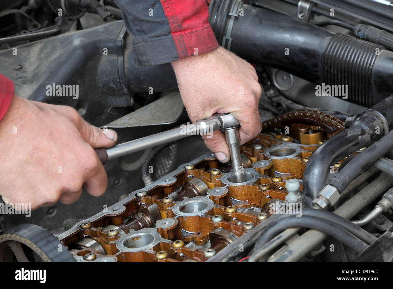 mechanic fixing spark plug to open car engine with ratchet visible D9T962