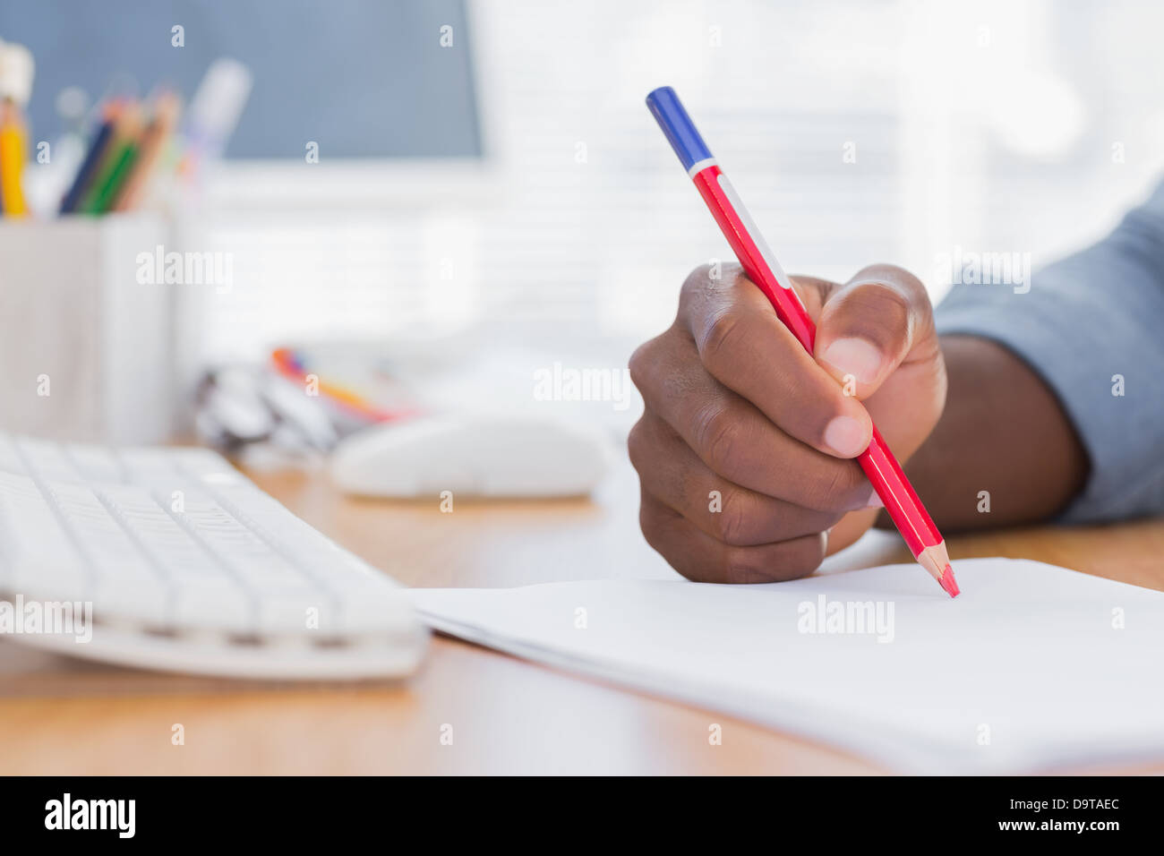 Man drawing with a red pencil on a desk Stock Photo