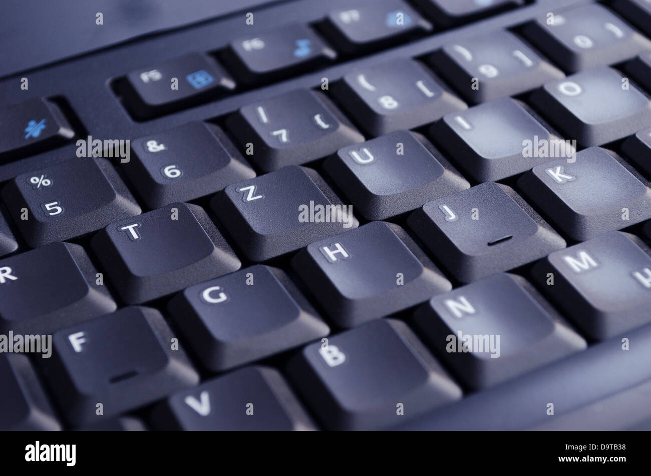 A black keyboard illuminated by the computer screen. Selective Focus. Stock Photo