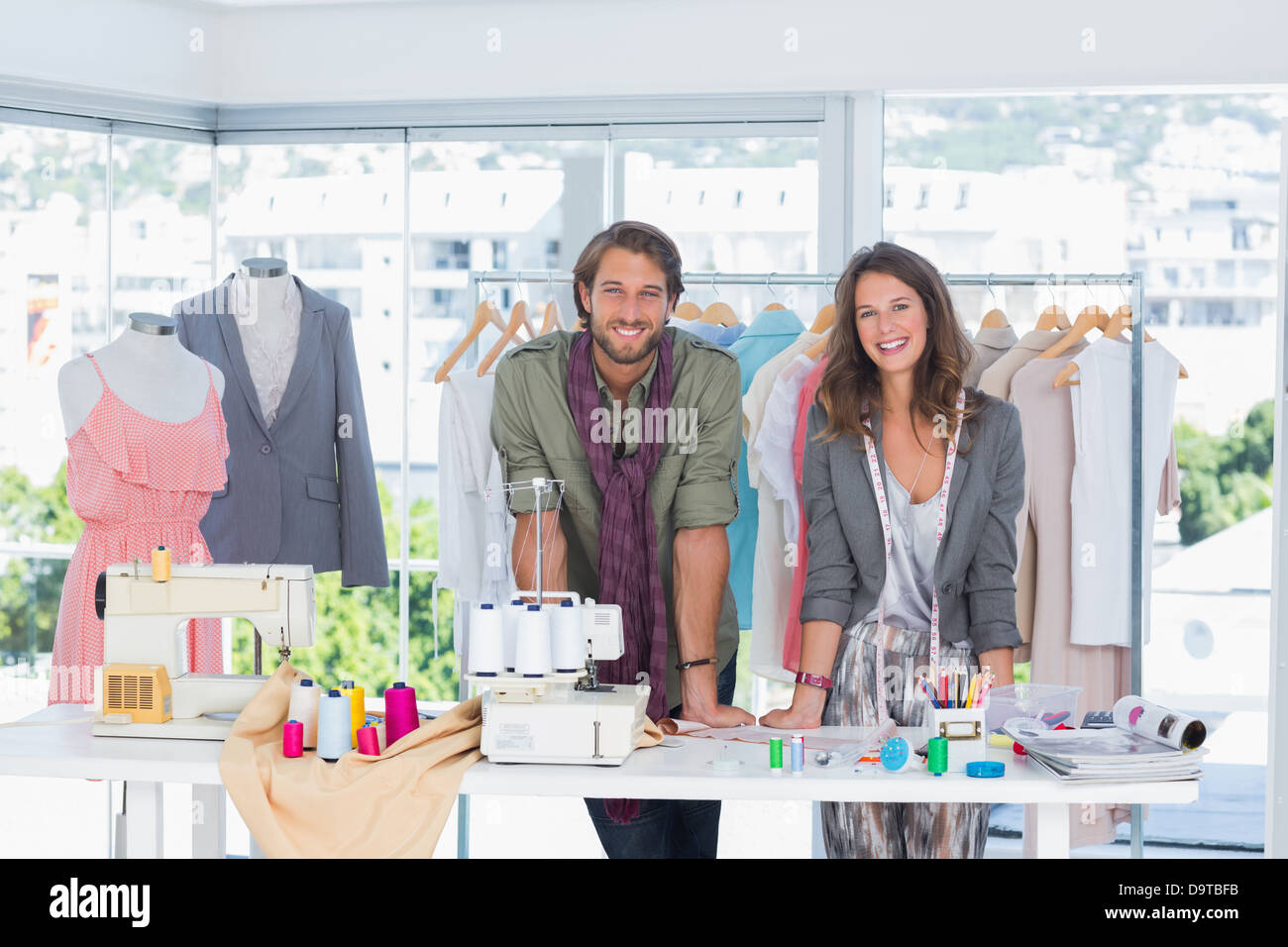Smiling fashion designers leaning on desk Stock Photo - Alamy