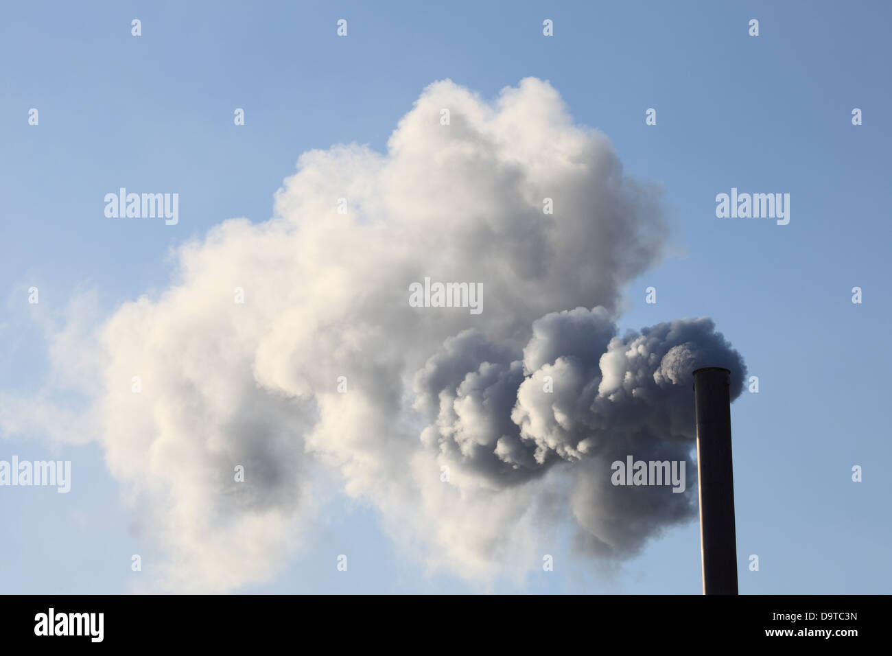 Factory smokestack blowing fume into the atmosphere Stock Photo