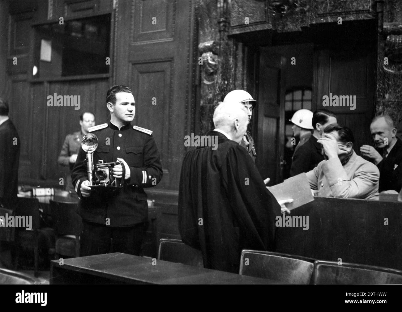 The picture of a colleague shows Soviet photographer Yevgeny Khaldei in uniform in the court room of the Nuremberg Trials against German war criminals. Main defendant Hermann Göring  covers his face with his hand. Stock Photo