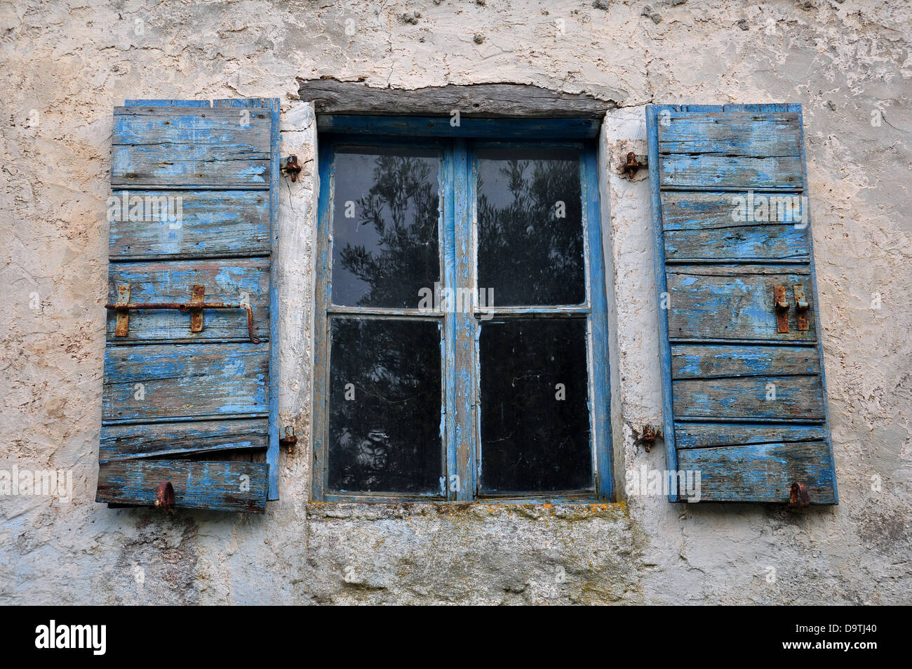 Wooden window shutter with chipped blue paint and textured wall of old ...
