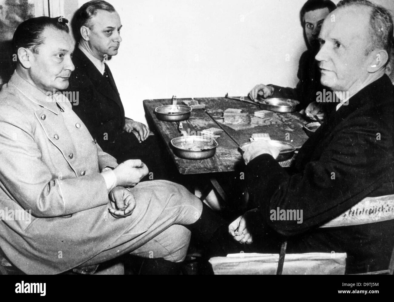 War criminals of the Nazi regime (left to right) Hermann Göring, Alfred Rosenberg, Baldur von Schirach and Karl Dönitz sit at a wooden table with metal plates and pieces of bread during the Nuremberg Trials in 1946.    Photo: Yevgeny Khaldei Stock Photo