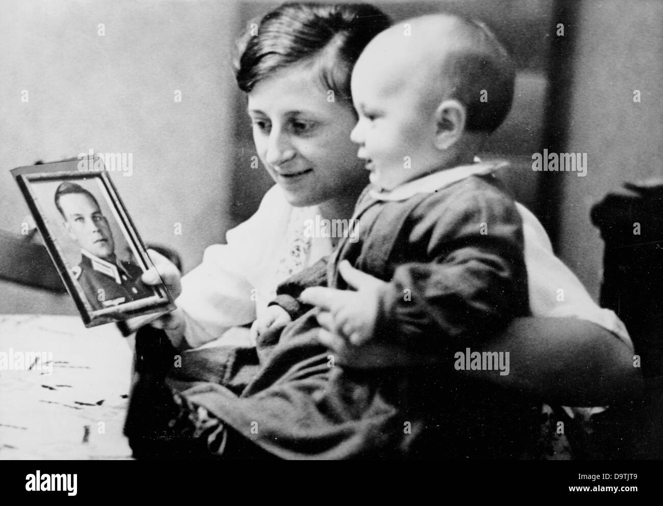 A woman and her child looks at a photo of her husband, who has gone to war as a soldier of the German Wehrmacht. Place unknown. Motive from the National Socialist Propaganda! from 20 November 1939. Fotoarchiv für Zeitgeschichte Stock Photo