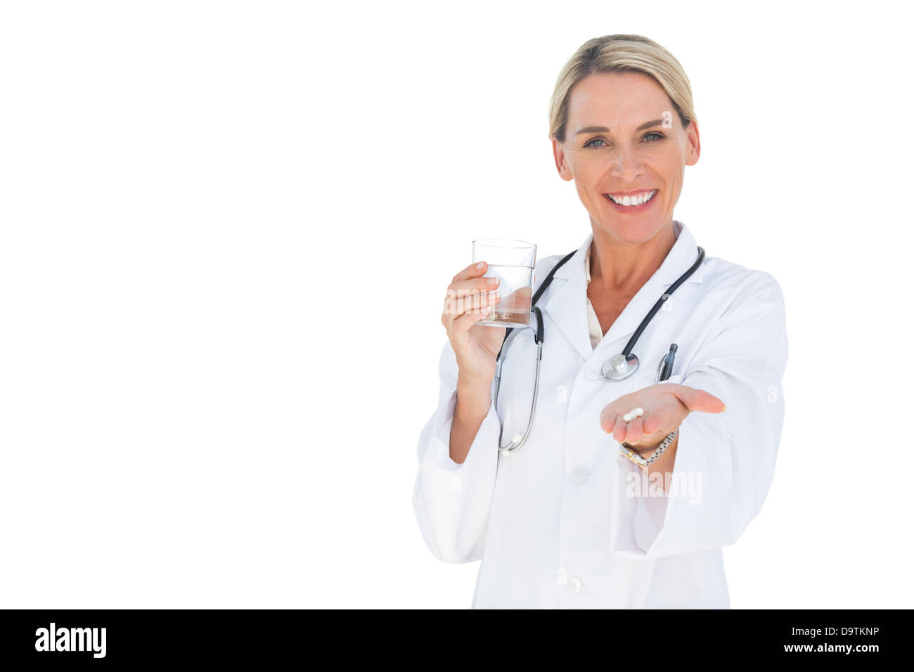 Smiling doctor holding out pills and water glass Stock Photo
