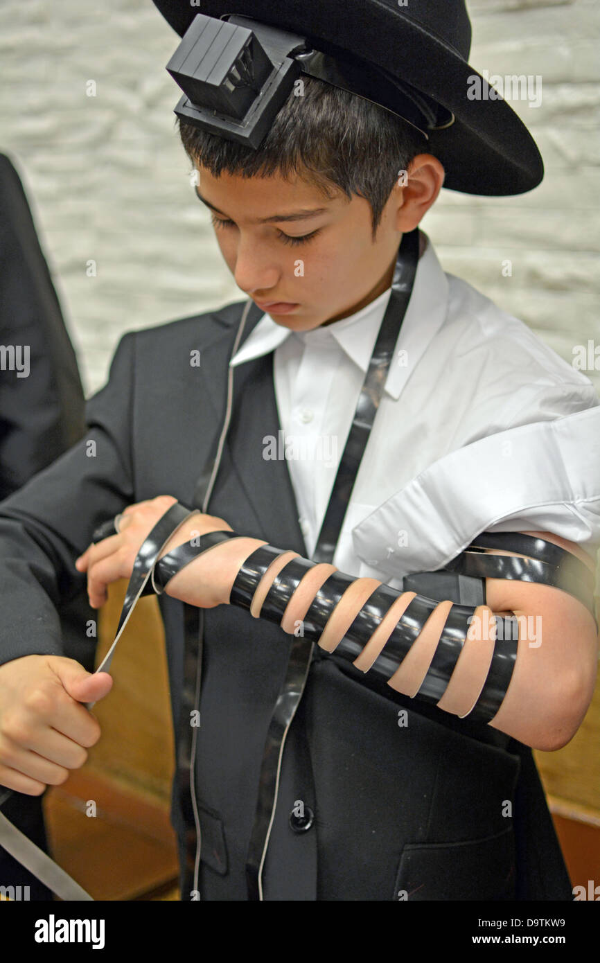 Young religious Jewish boy puts on phylacteries - tefillin - for the first time at a synagogue in Brooklyn, New York Stock Photo - Alamy