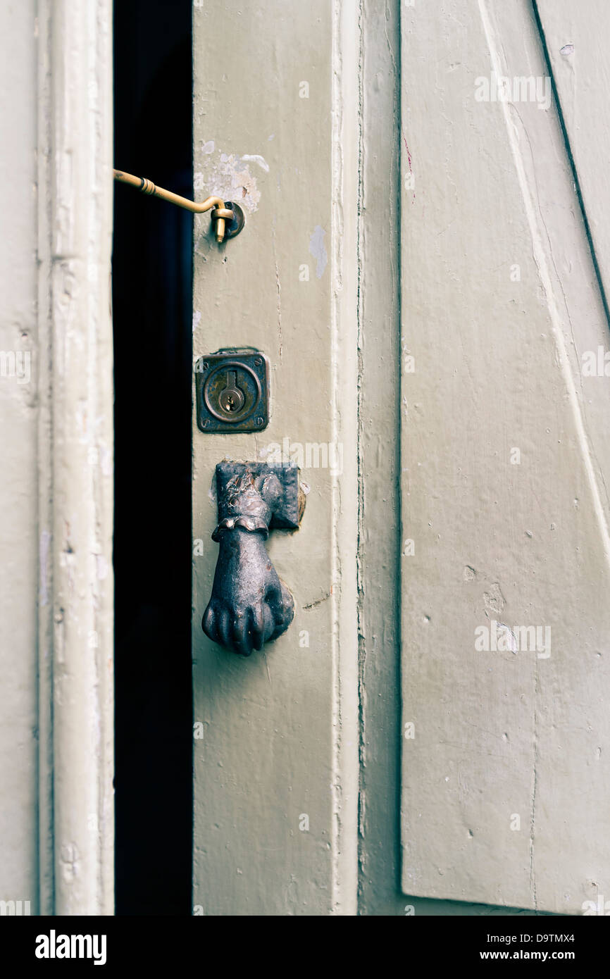 Open door held on latch with hand shaped knocker, close up, Stock Photo