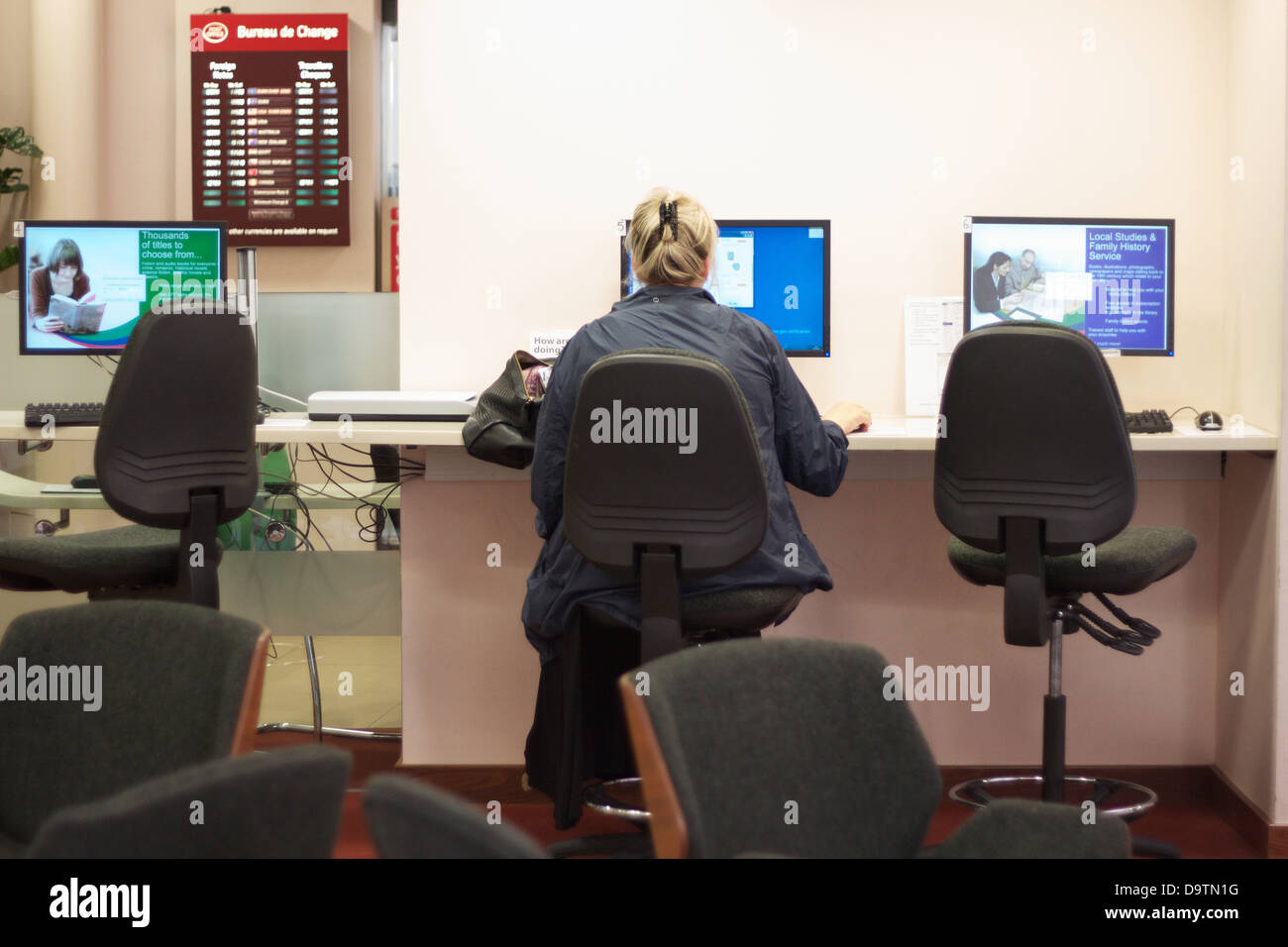 A woman sits a public computer in a council building in the UK Stock Photo