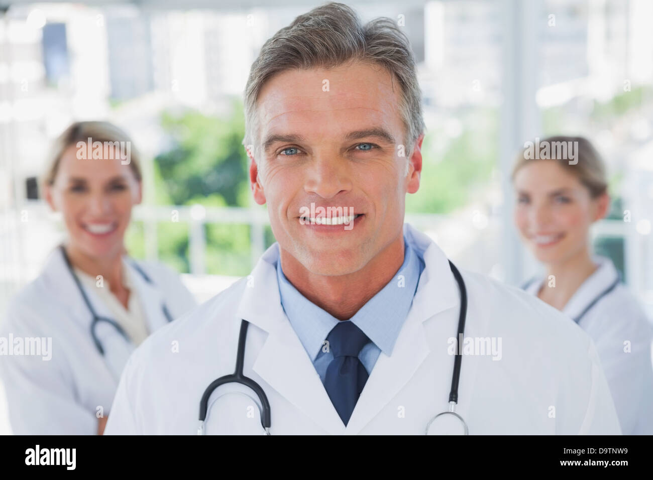 Charismatic doctor standing with colleagues Stock Photo