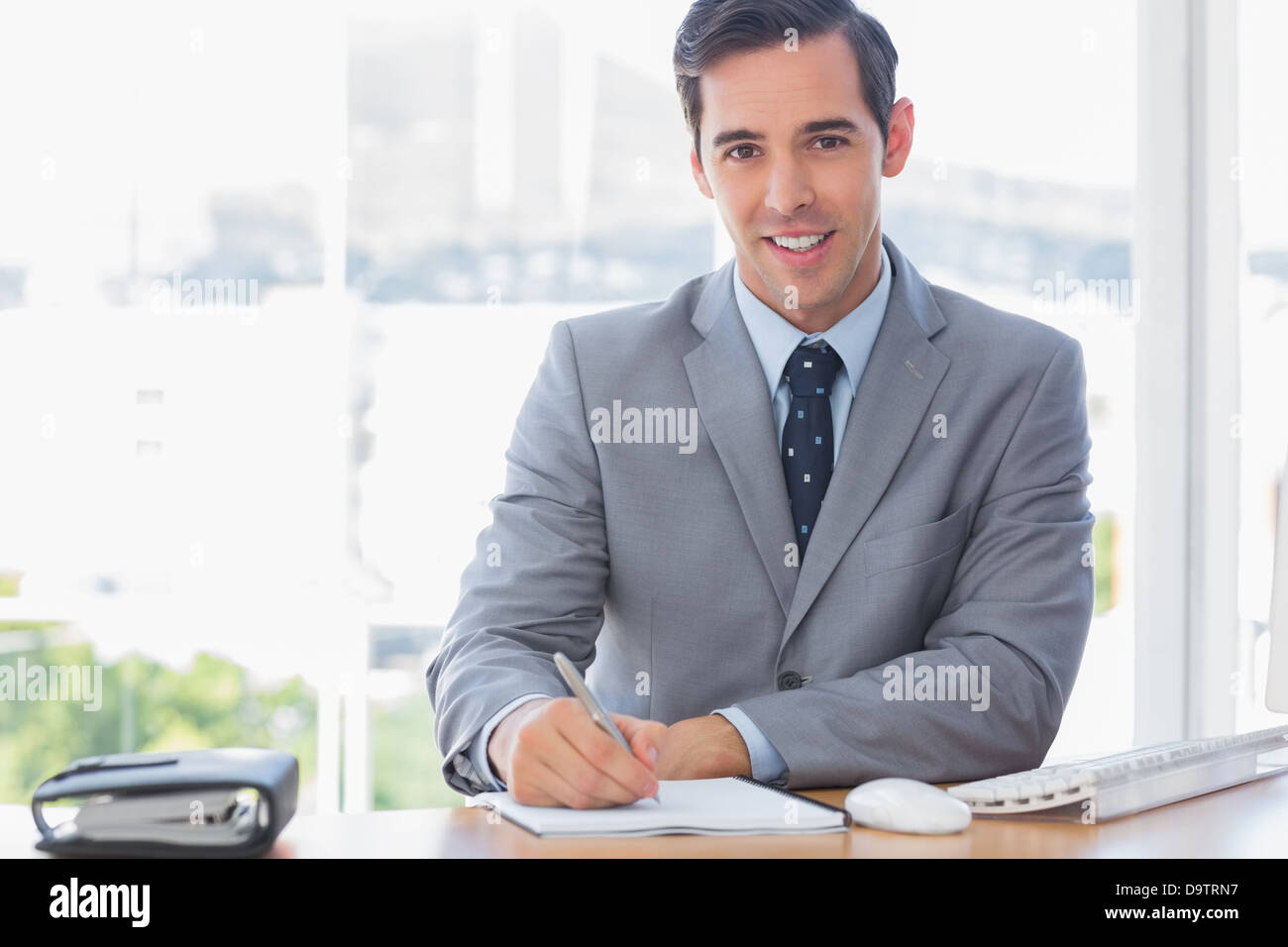 Smiling businessman writing at his desk Stock Photo - Alamy