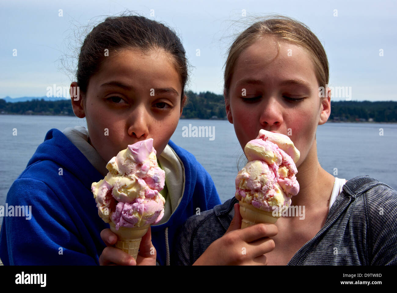 Two pretty young girls tasting each other's huge ice cream cones Campbell River BC Canada Discovery Fishing Pier Stock Photo