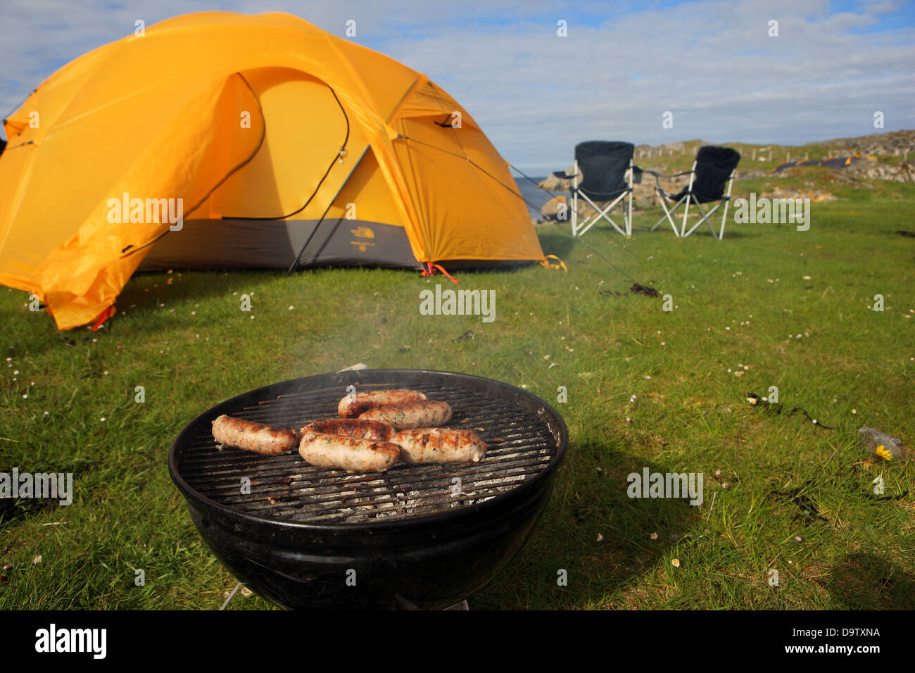 Sausages cooking whist camping with tent and chairs by the sea in Scotland Stock Photo