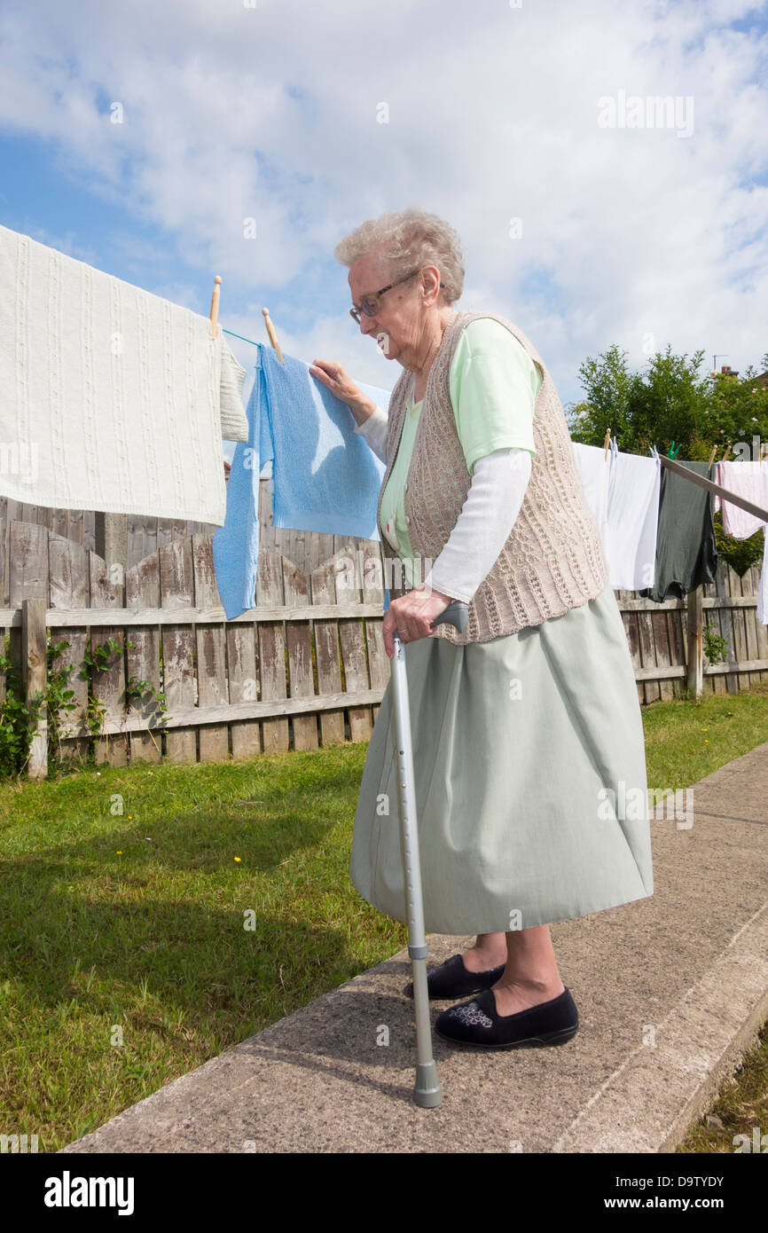 Ninety year old woman, pensioner with walking/zimmer frame checking washing on line. UK Stock Photo