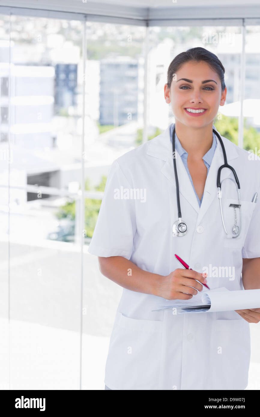 Doctor smiling at camera and holding clipboard and pen Stock Photo - Alamy