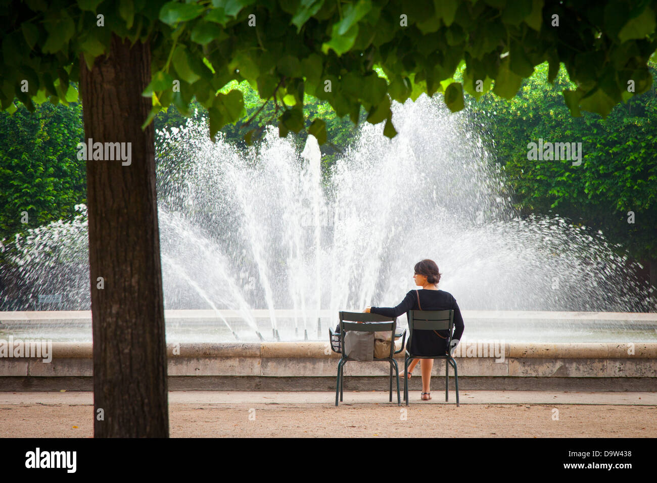 Woman relaxing at the fountain in the Garden of Palais Royal, Paris France Stock Photo