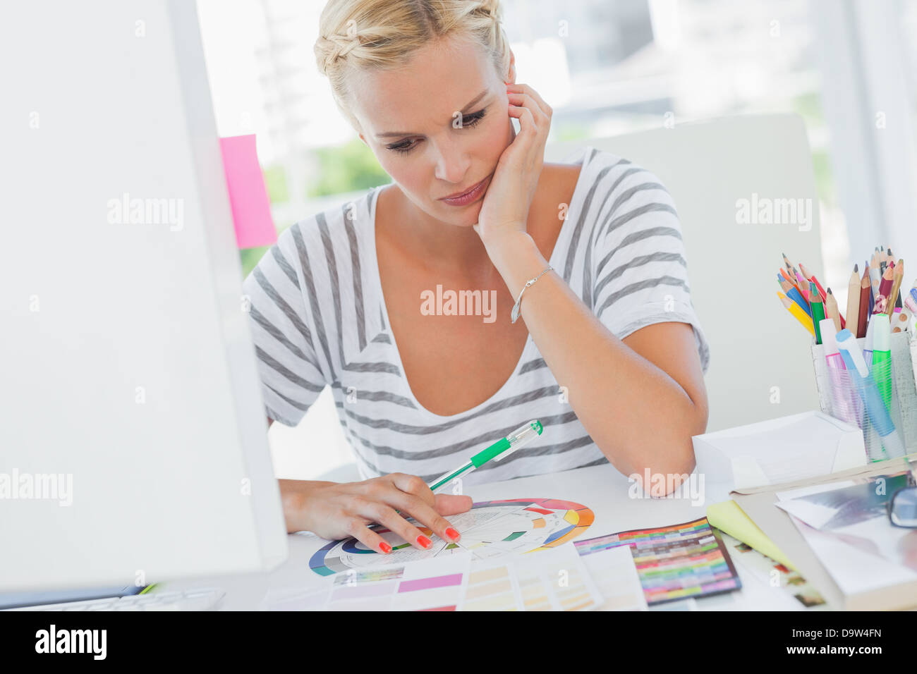 Thoughtful interior designer looking at colour wheel Stock Photo - Alamy