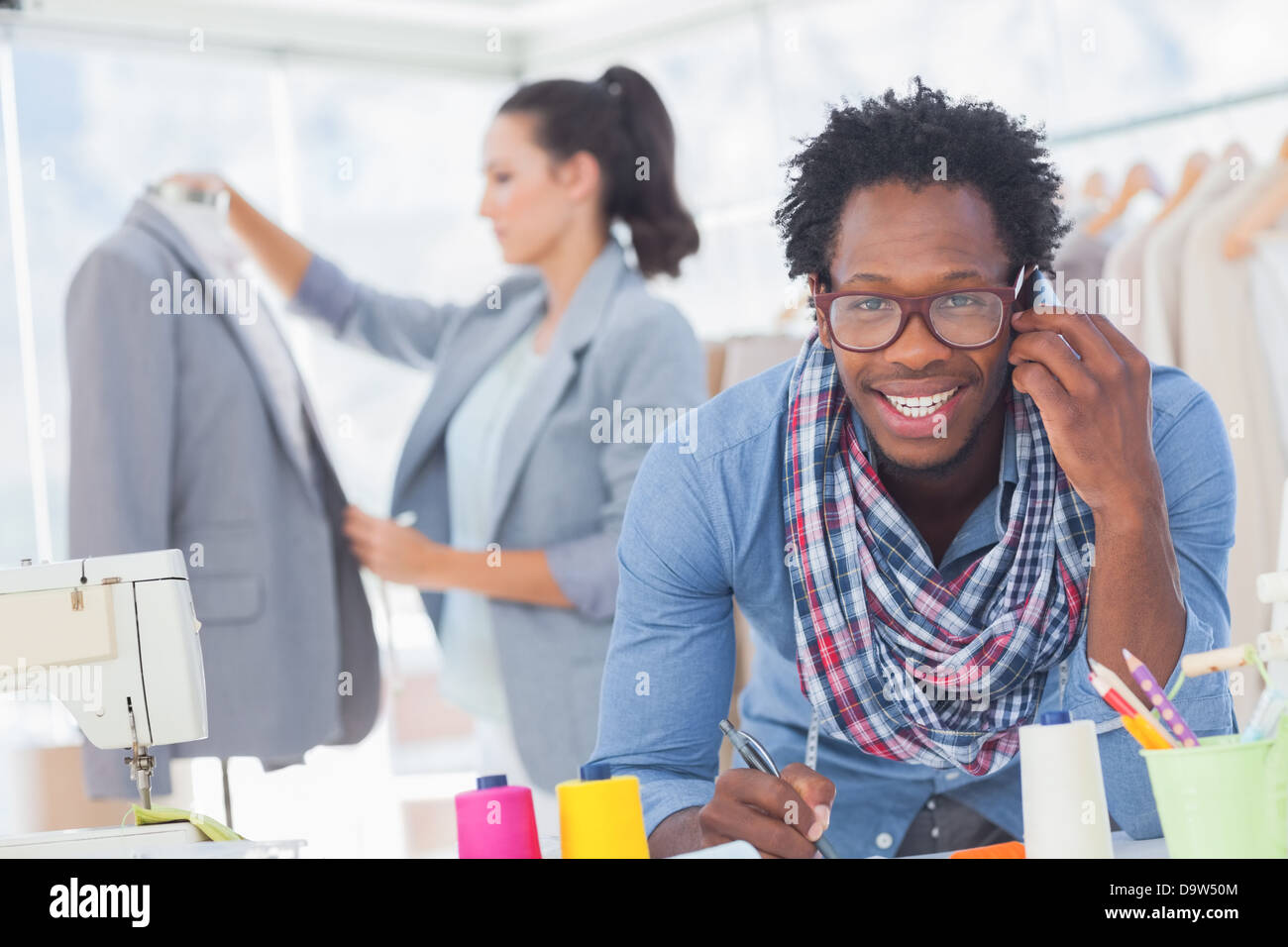 Smiling fashion designer on the phone Stock Photo - Alamy