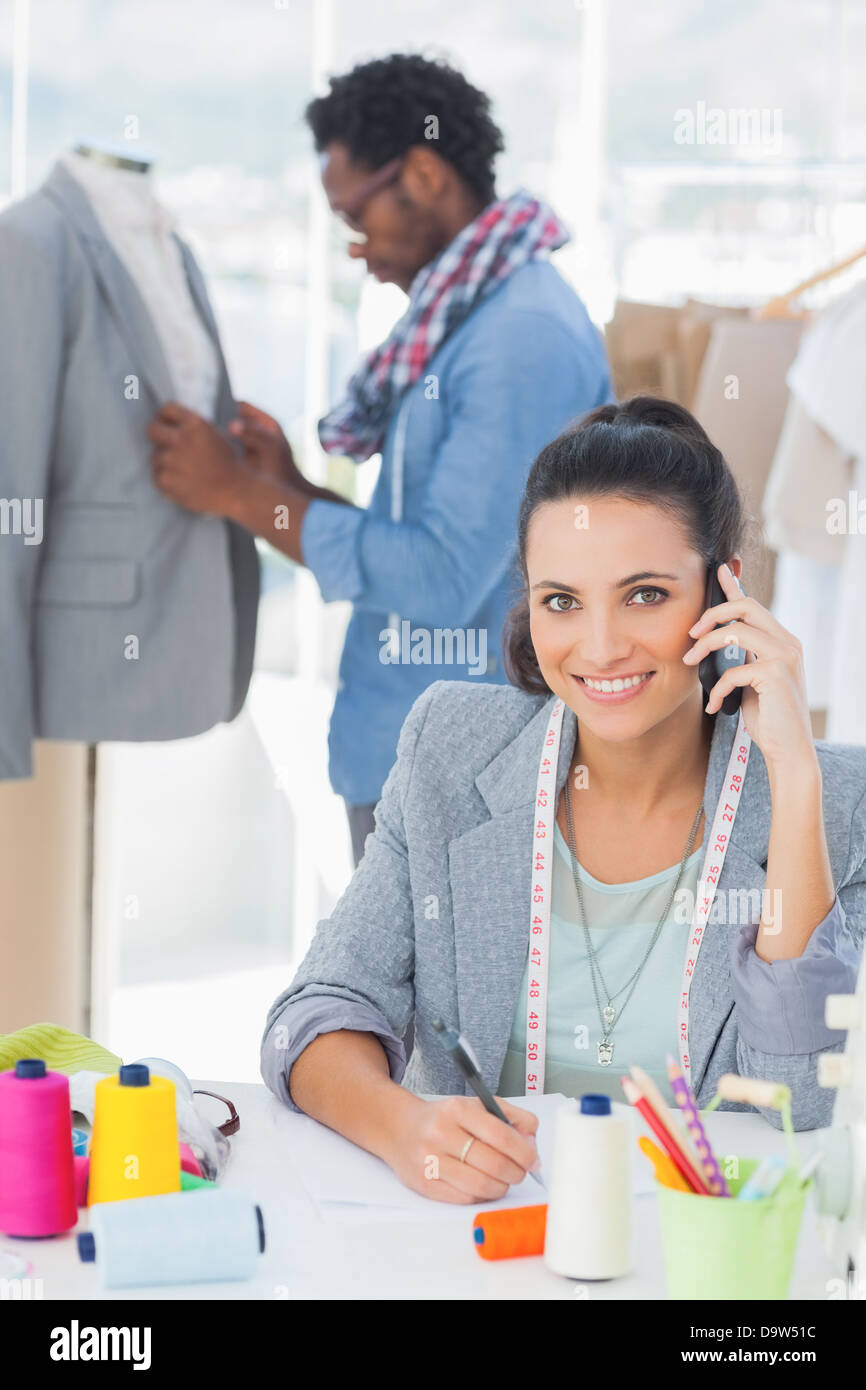 Smiling fashion designer calling Stock Photo - Alamy