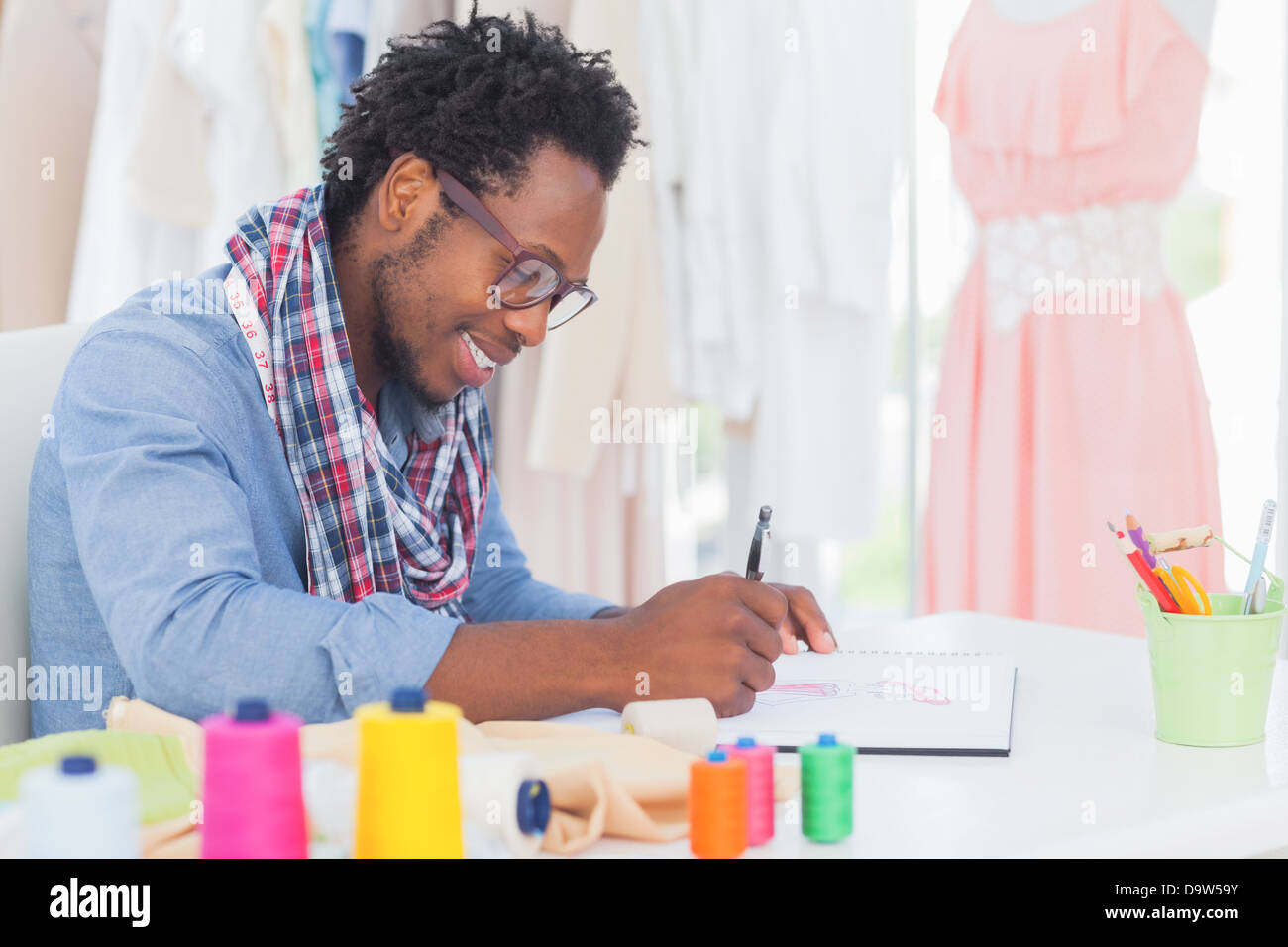 Attractive fashion designer sitting at his desk drawing Stock Photo - Alamy