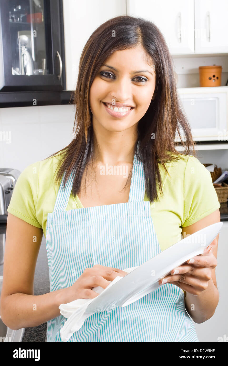 pretty young woman drying dishes in kitchen Stock Photo