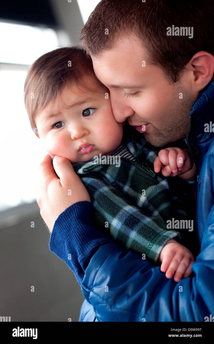 Father hugging displeased toddler (12-17 months) Stock Photo